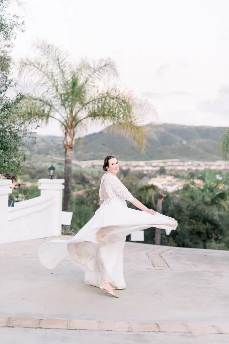 Bride swinging her skirt out to the side with the palms and the hills behind her
