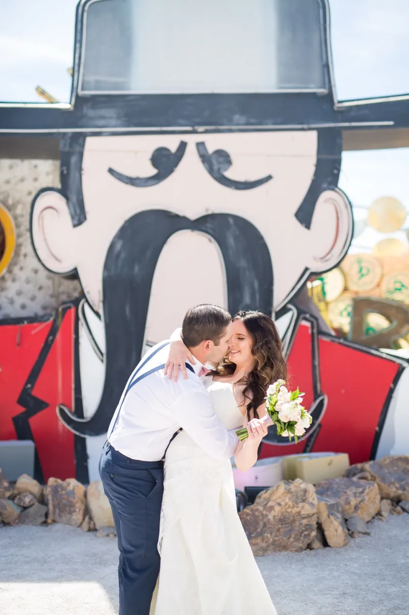 Couple kissing beneath a large painted sign face in the boneyard