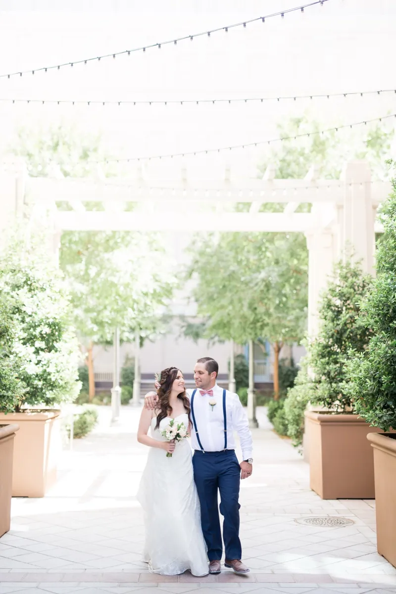 Couple walking a garden path between big square planters with strings of cafe lights crossing above them