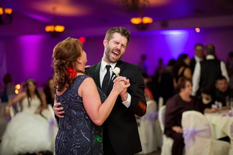 Groom sharing a parent dance on the reception floor with the tables behind them