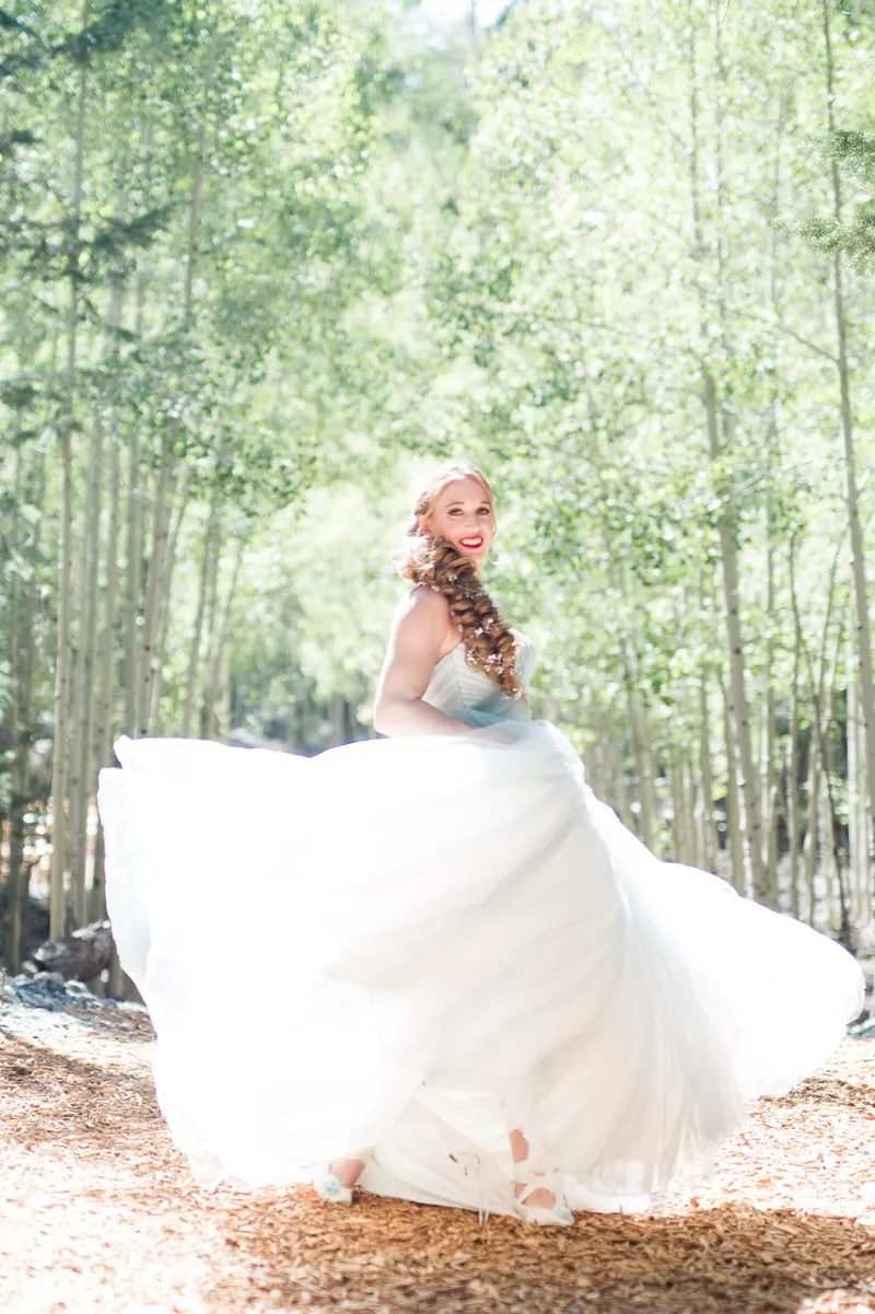 Bride swinging her skirt out wide in a clearing between the aspens