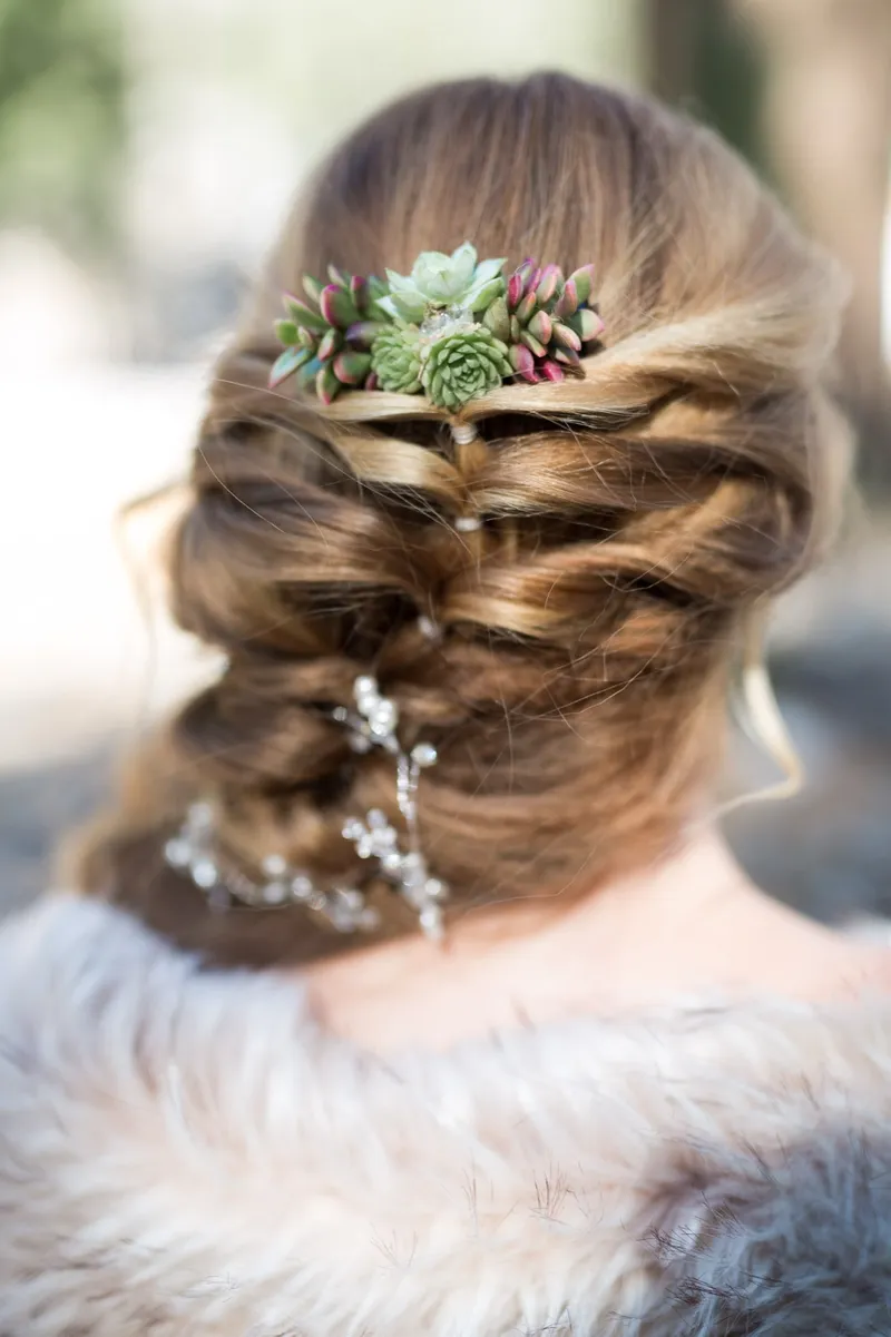 Close view of the bride's braided updo pinned with succulents and a crystal vine