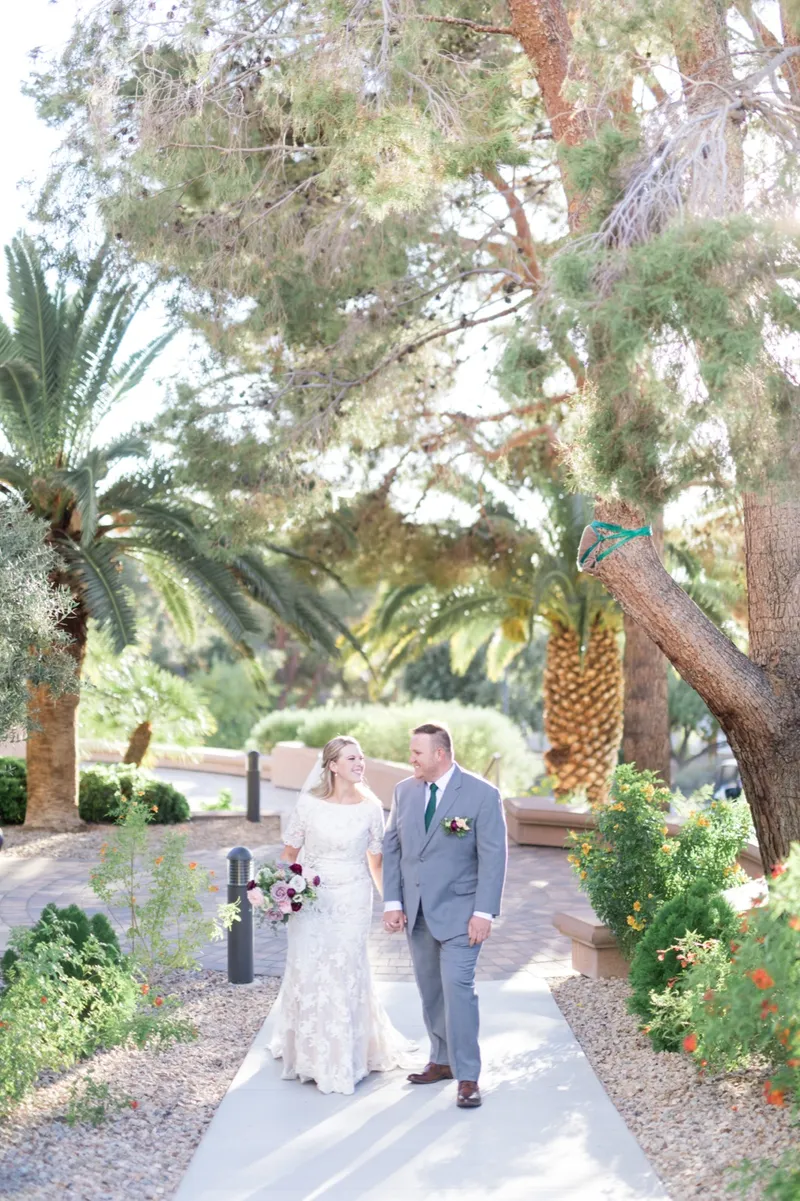 The couple turned toward each other on the path under a tall date palm, the bride's train laid out behind her