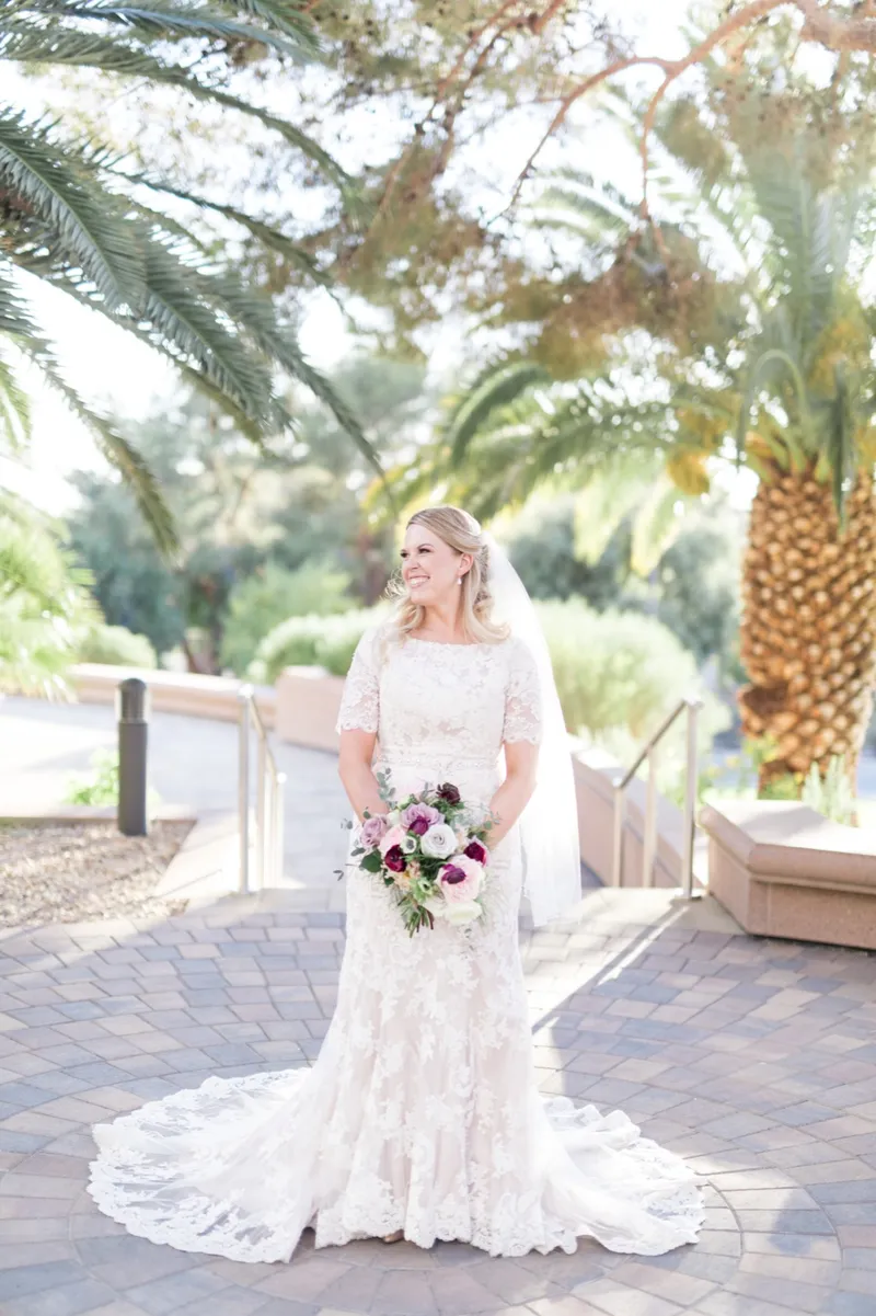 The bride standing alone on the pavers with her bouquet at her waist and her train fanned out behind her