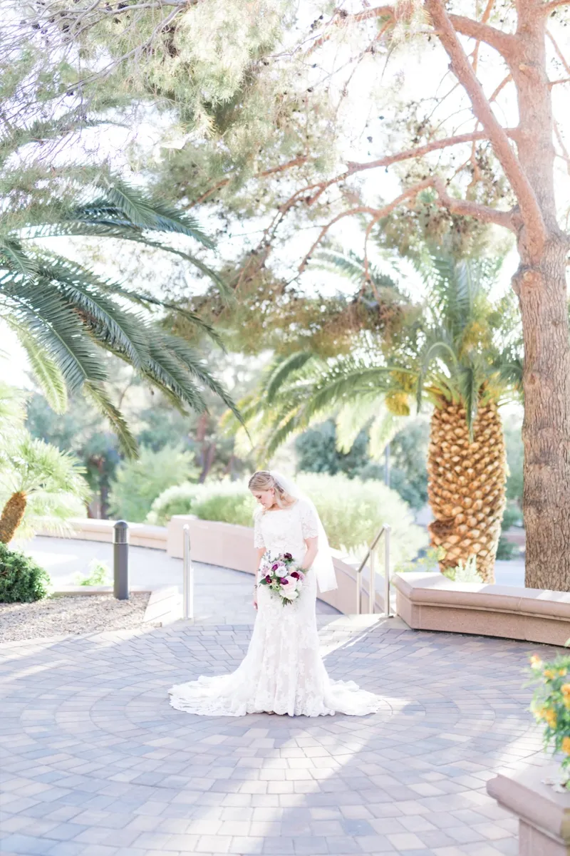 A wide frame with the bride small on the walkway and the palms arching over the whole picture