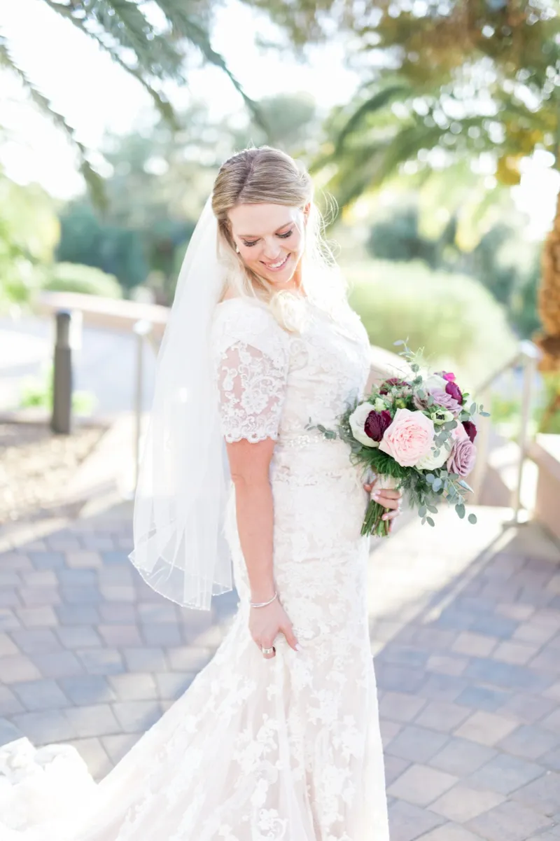 The bride looking down and smiling with her bouquet held low at her side