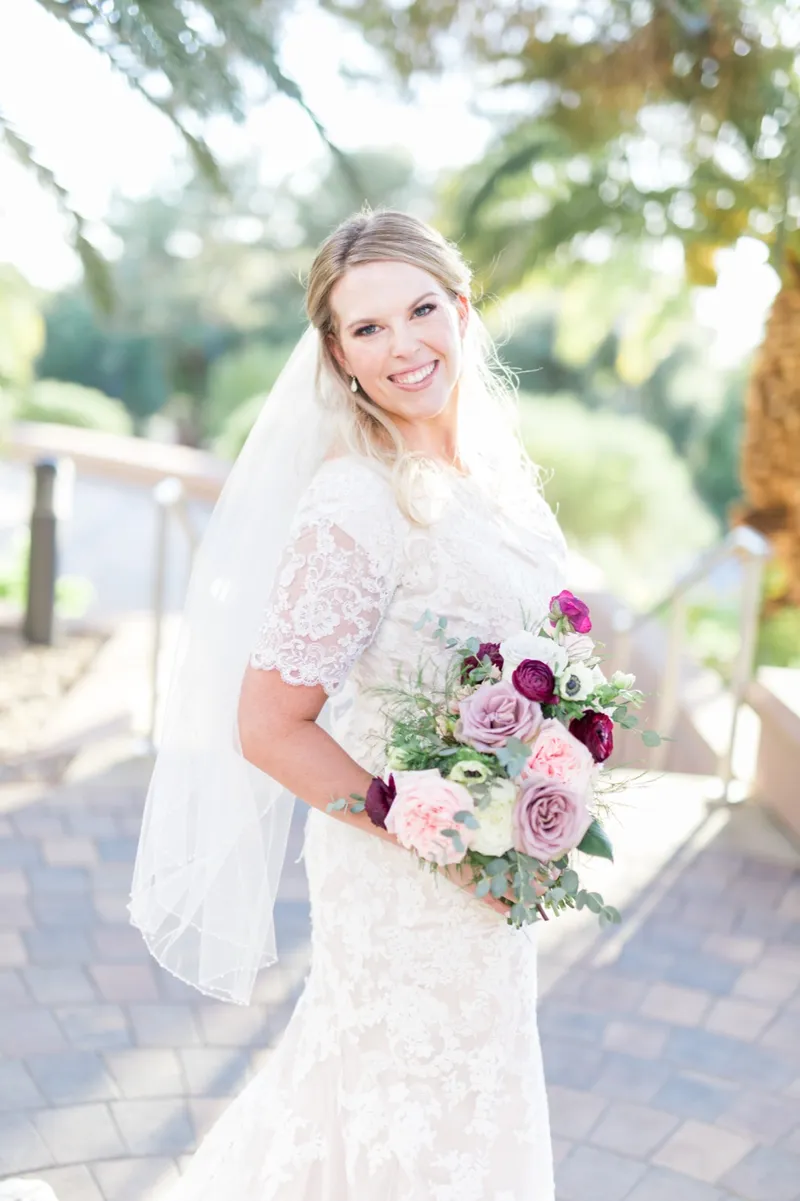 The bride in her veil smiling with her bouquet lifted to her shoulder