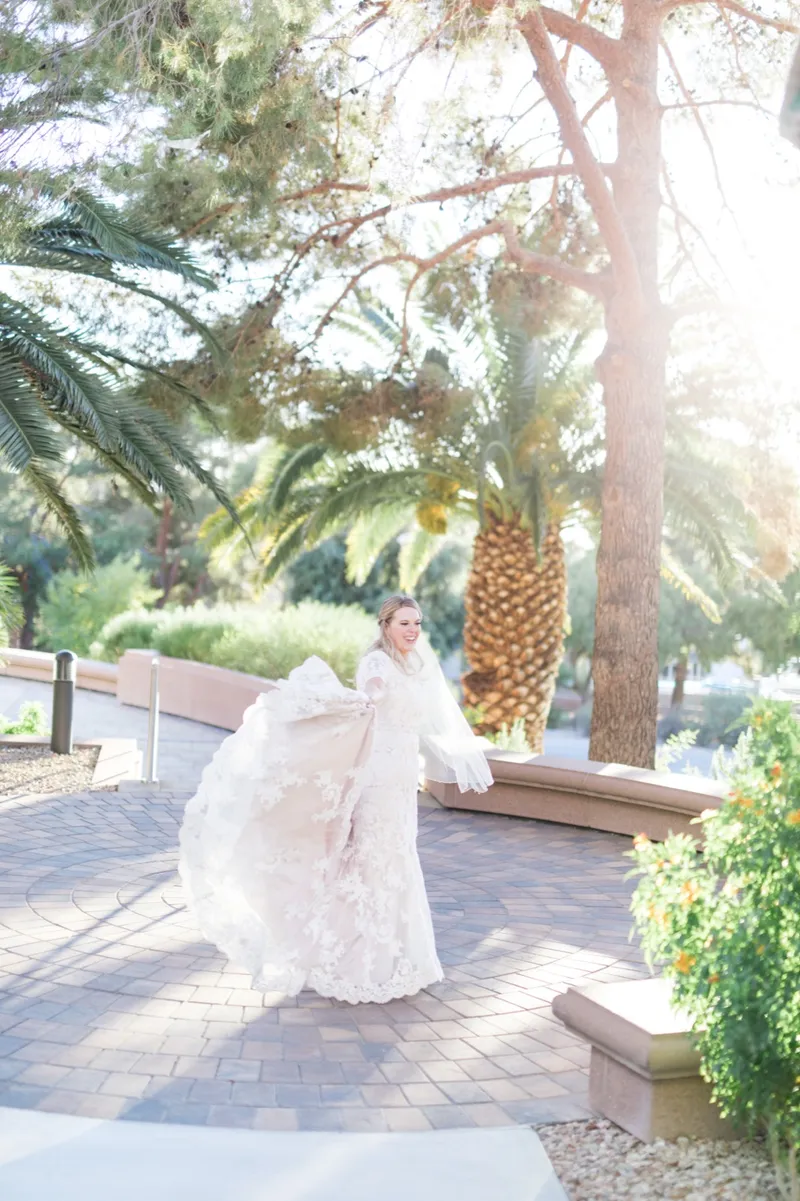 The bride walking away down the path with her lace train trailing across the pavers behind her