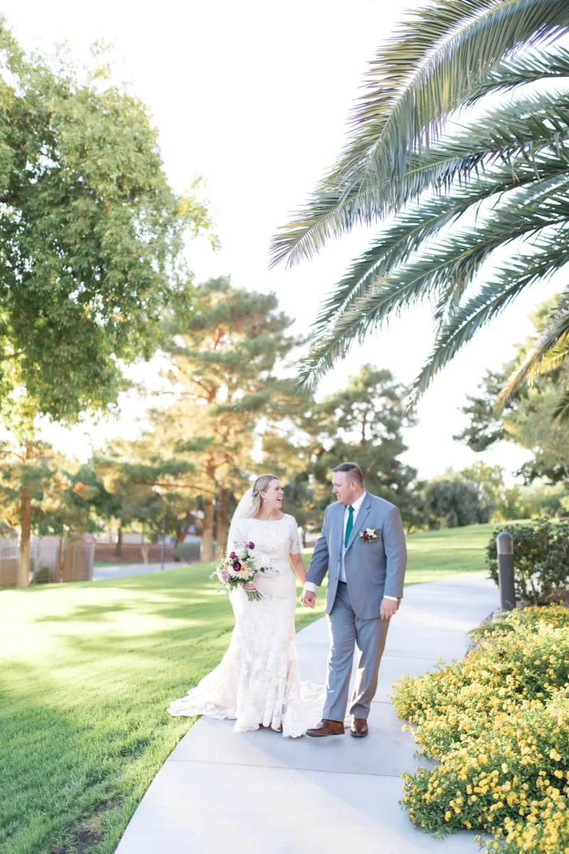 The couple walking a path across the temple lawn with grass on one side and trees on the other