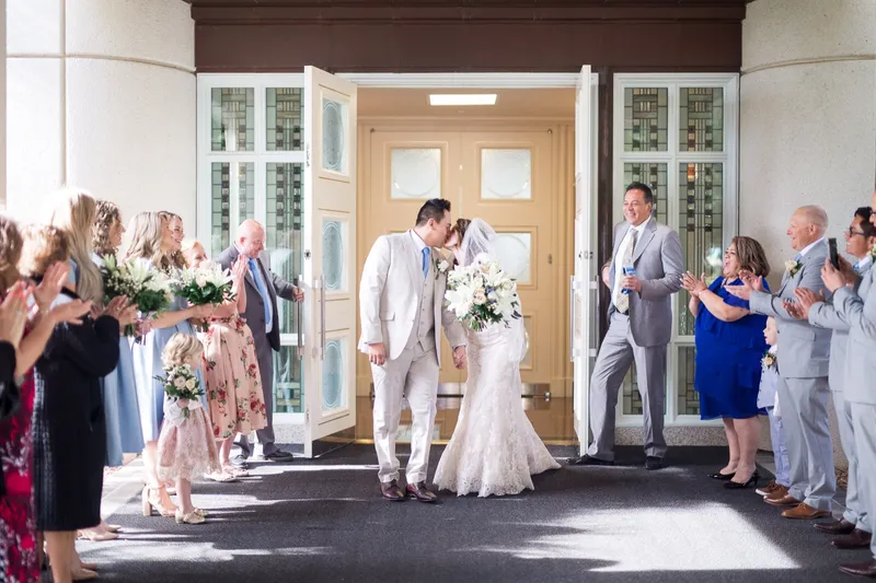 The couple kissing in the open temple doorway while two long lines of family and friends clap them out