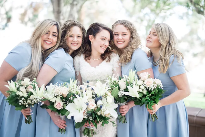 The bride with four bridesmaids in dusty blue dresses, all of them holding white bouquets