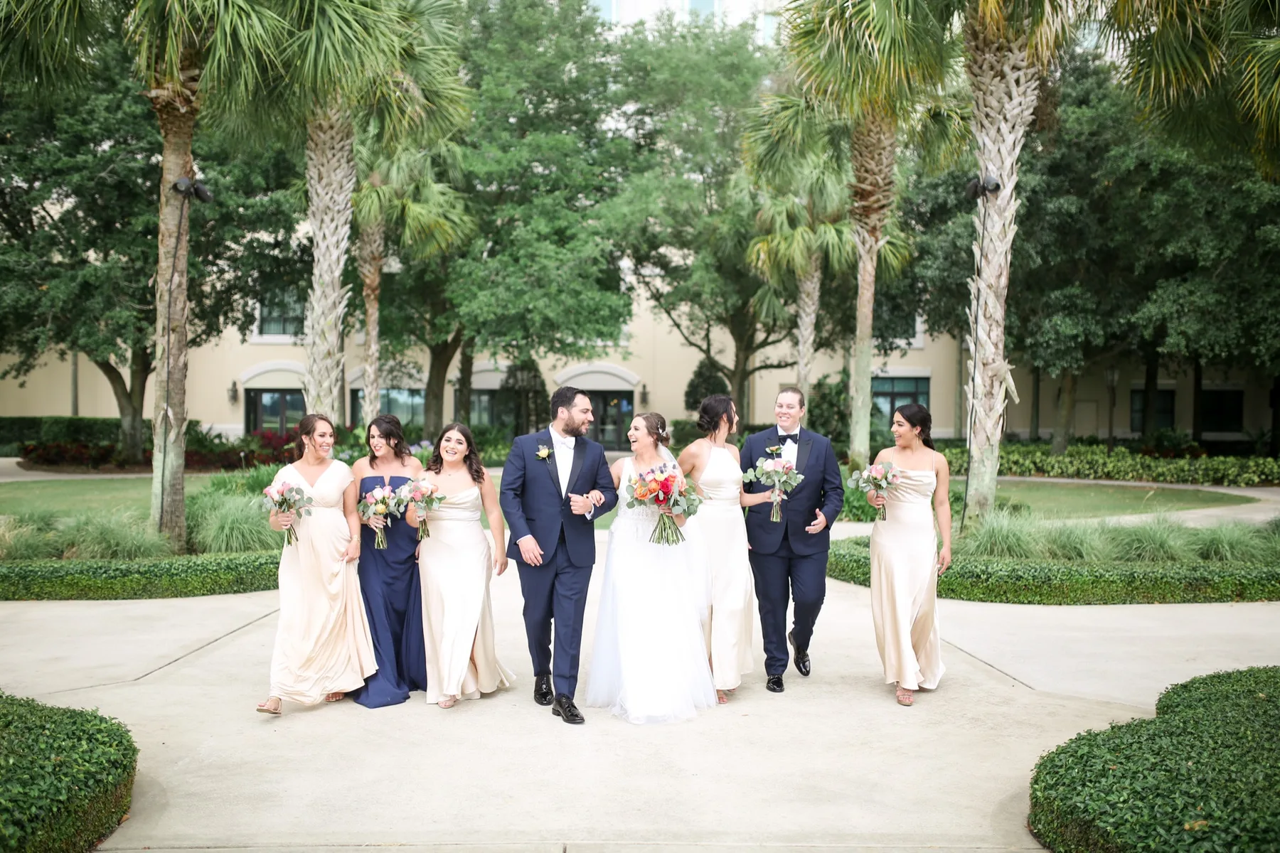 Bride and groom walking with their wedding party under palm trees