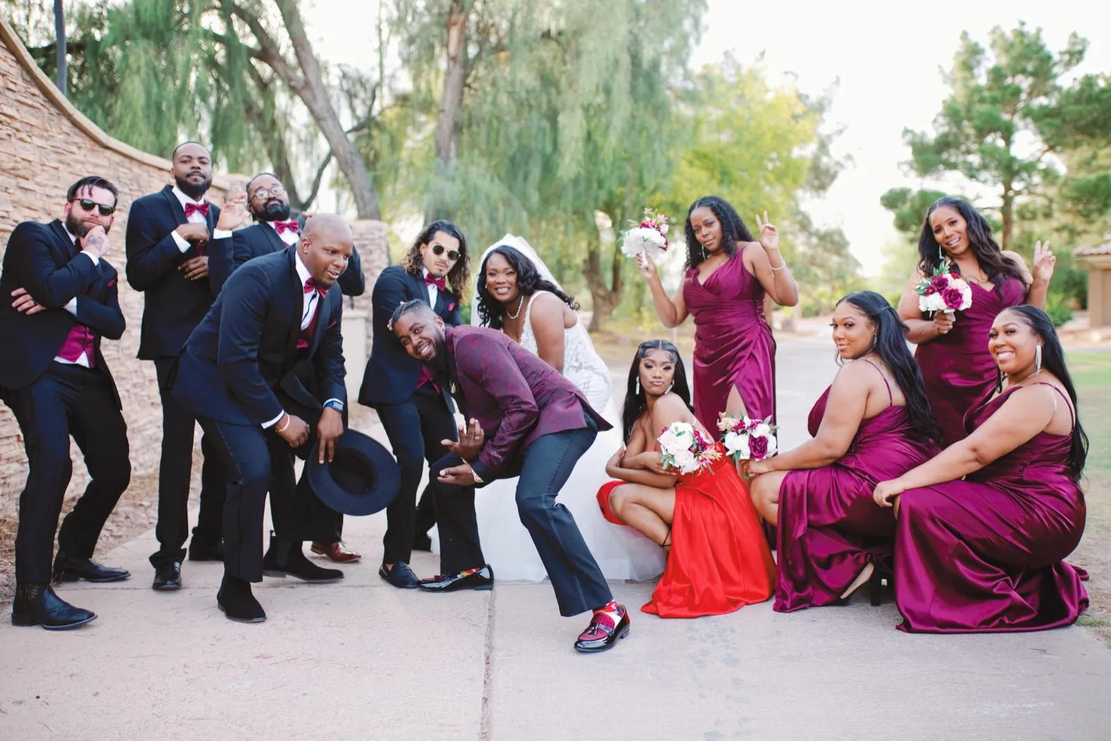 Wedding party in burgundy and black posing on the cart path under the willows