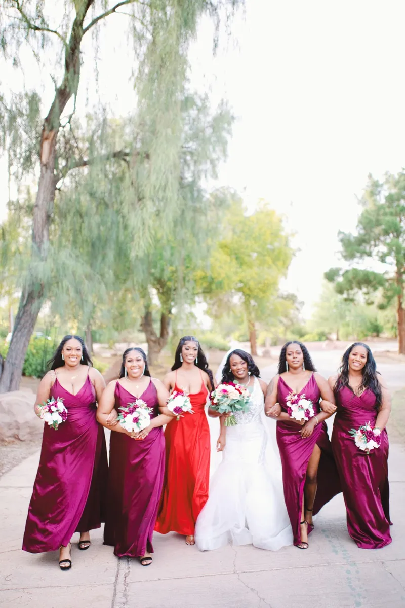 Bride and her bridesmaids walking the path together with the trees behind them