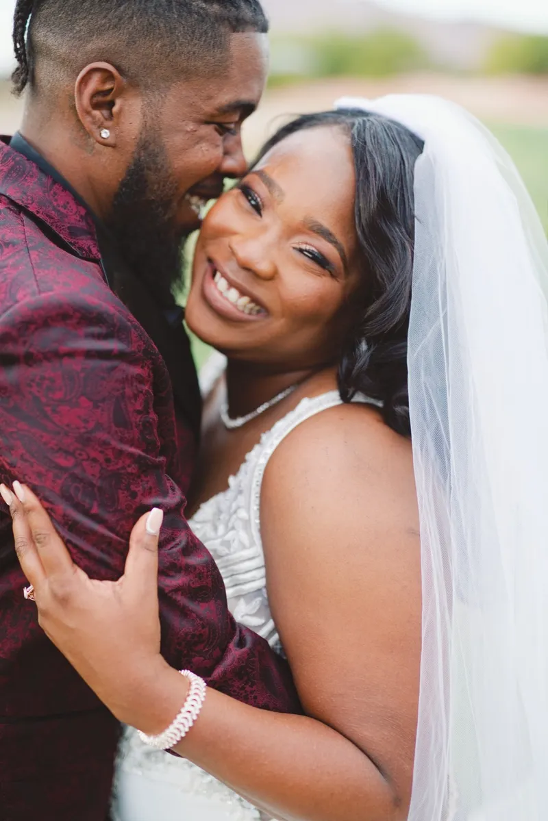 Close portrait of the groom kissing the bride's cheek beneath her veil