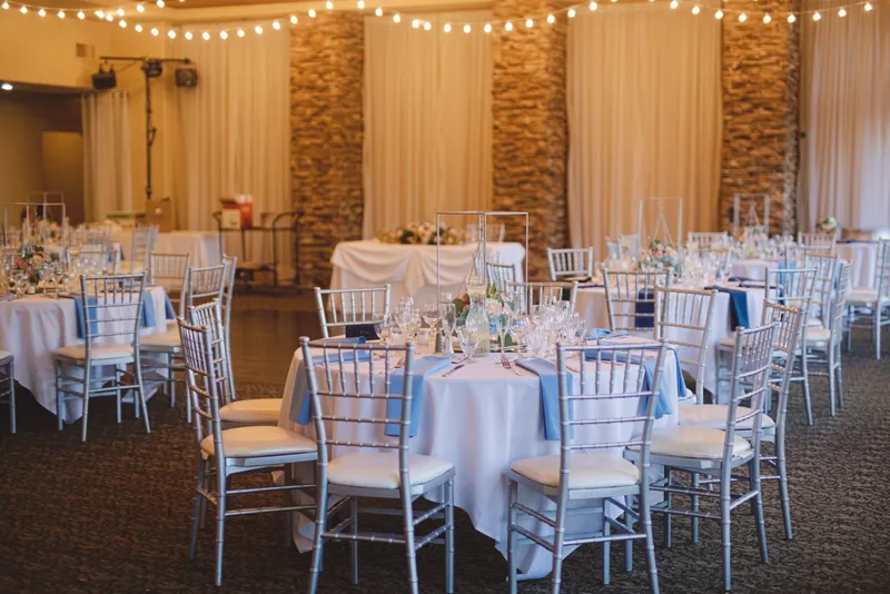 Reception room in dusty blue and white with cafe string lights strung across the whole ceiling