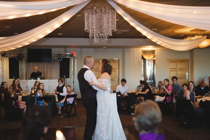 First dance under the draped ceiling and chandelier with guests seated around the room