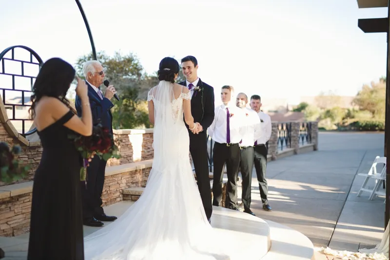 Couple standing with the officiant during the ceremony, the bride's train spread out on the ground behind her