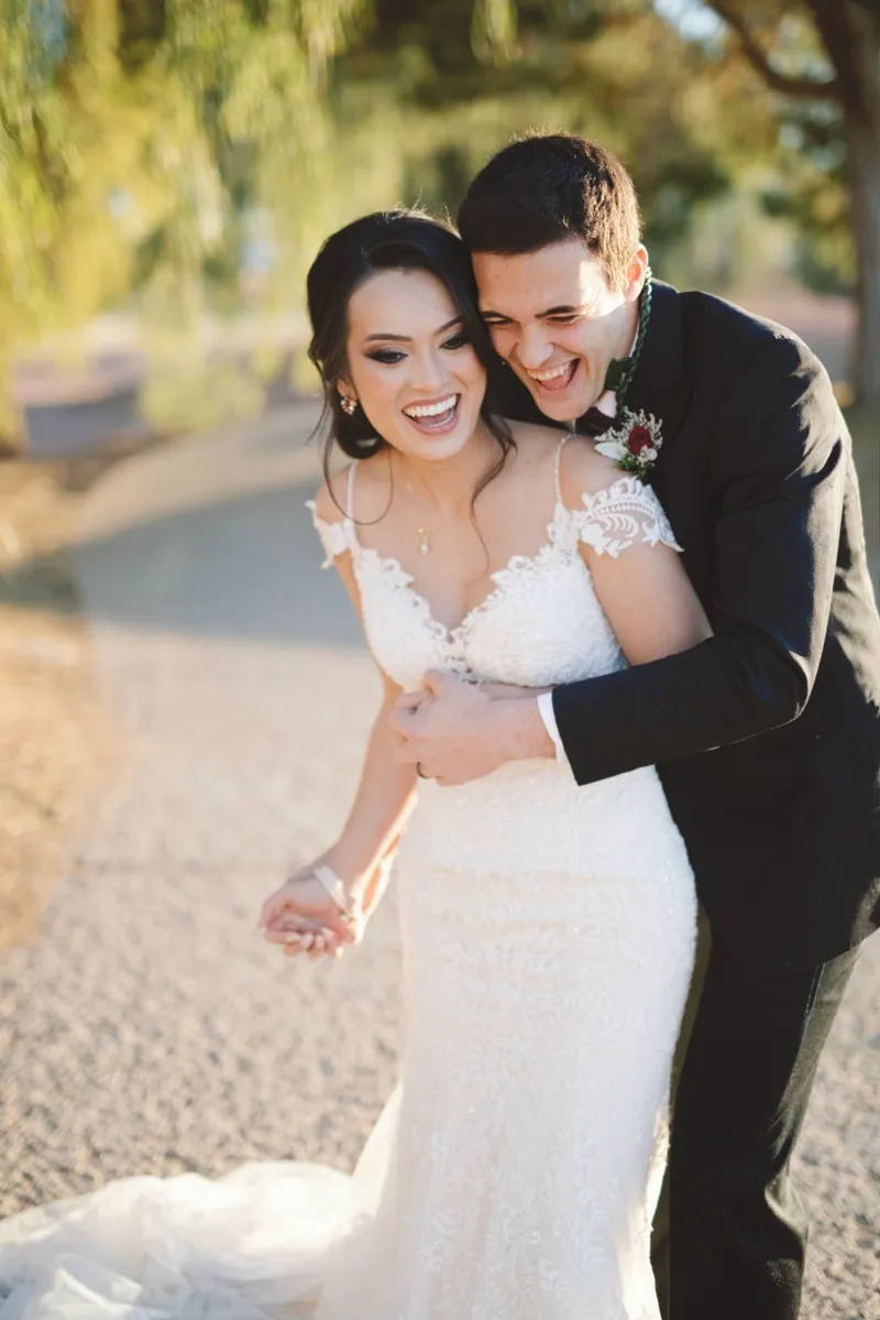 Couple laughing with his arms wrapped around her from behind on the path