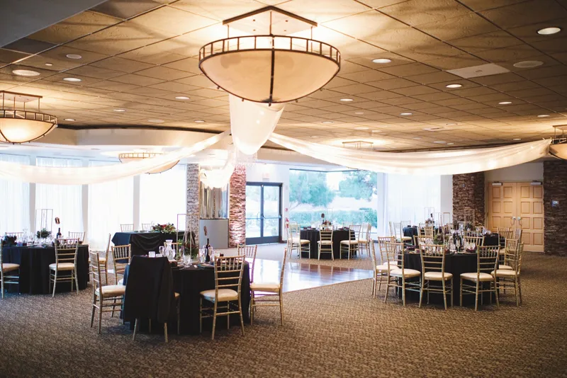 Wider view of the same room in black linens under the draped ceiling and a low pendant light