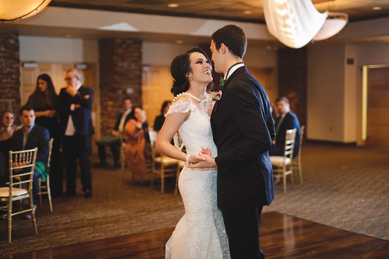 First dance on the wood floor with guests gathered in a ring around the couple