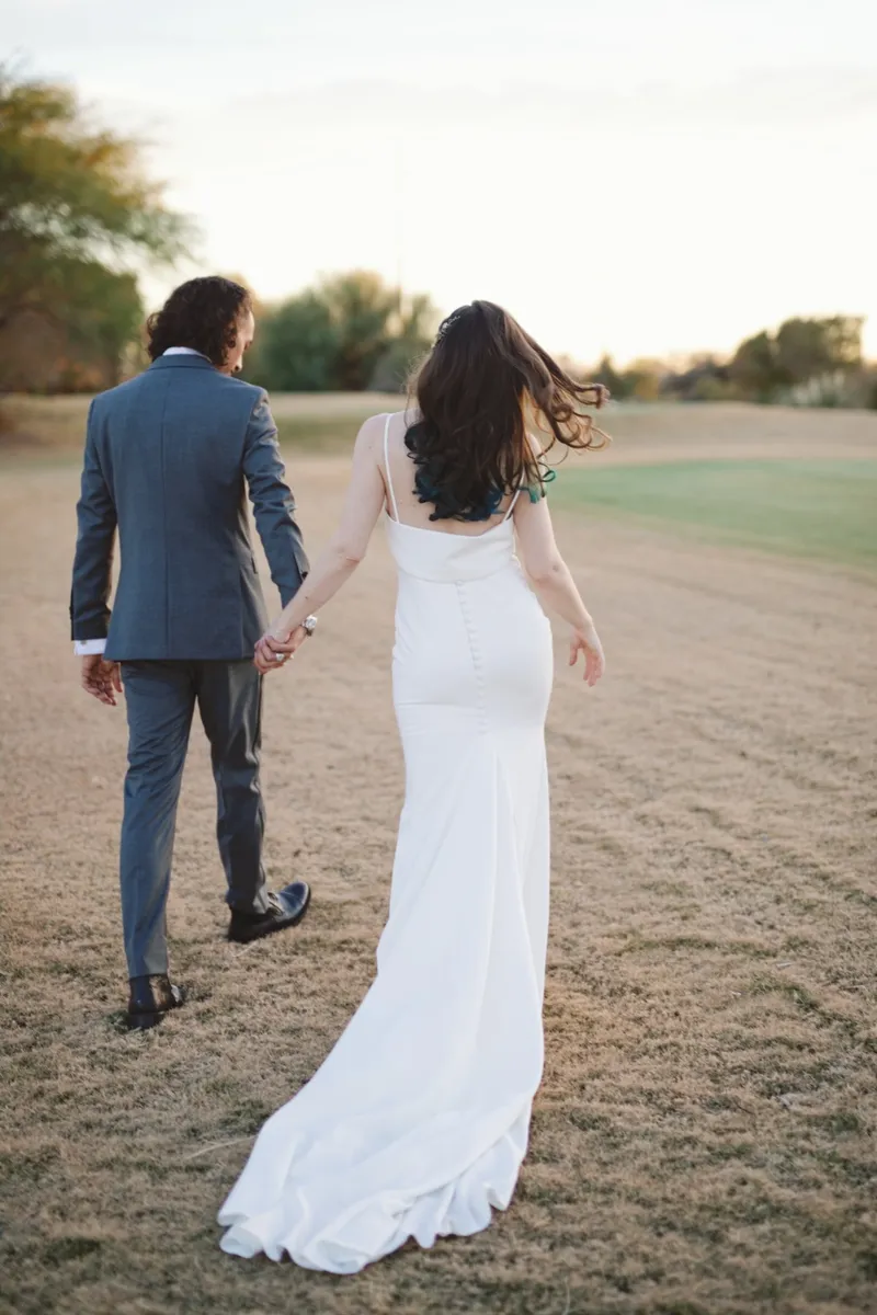 Couple walking away hand in hand across the fairway as the light goes flat at dusk