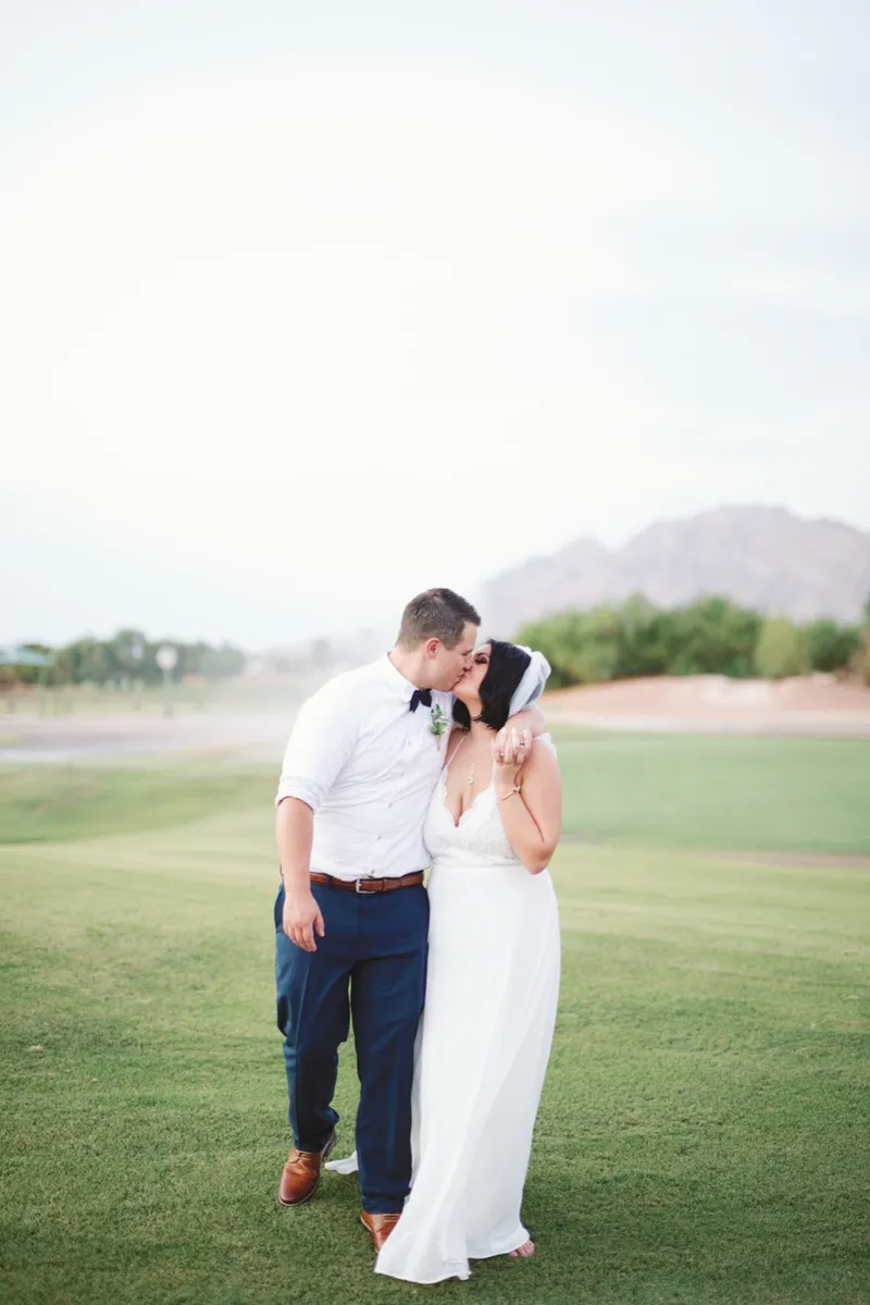 Couple kissing on the fairway with the mountain ridge far behind them