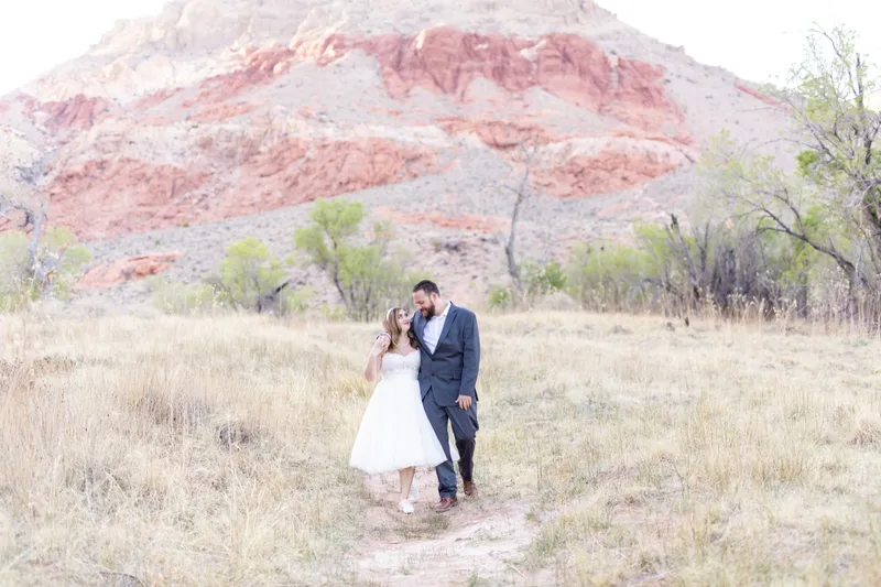 Couple kissing in the dry grass with the desert stretching behind them