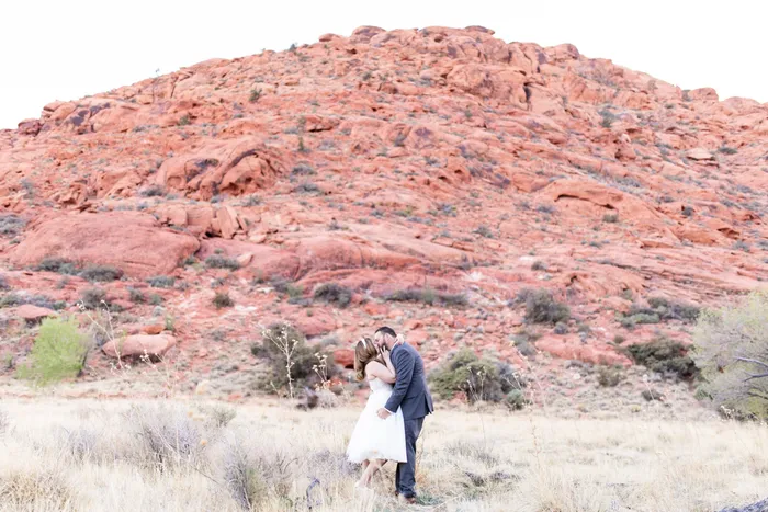 Bride and groom kissing among the red rocks outside Las Vegas