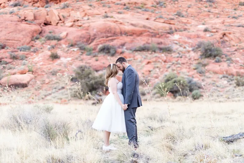 Couple standing forehead to forehead below the red canyon wall