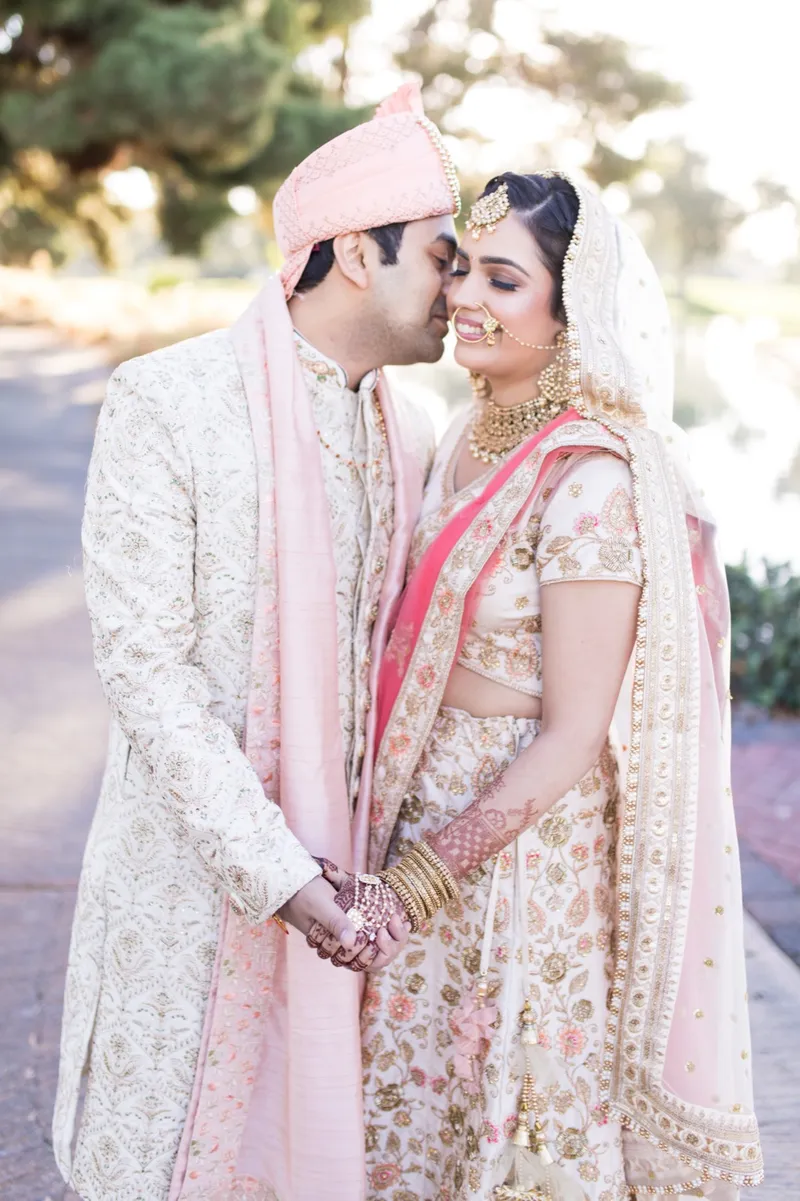 Groom leaning his head against the bride's as they stand together on the path