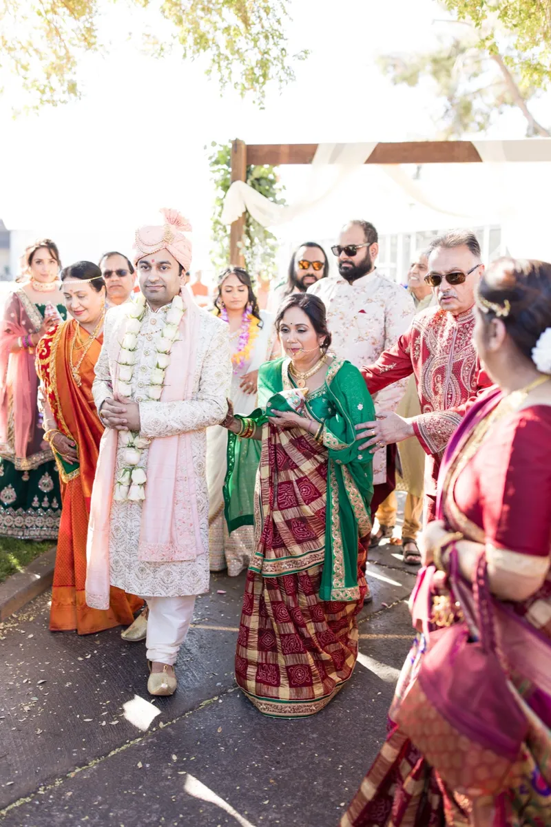 Couple in their flower garlands moving through a crowd of family after the ceremony