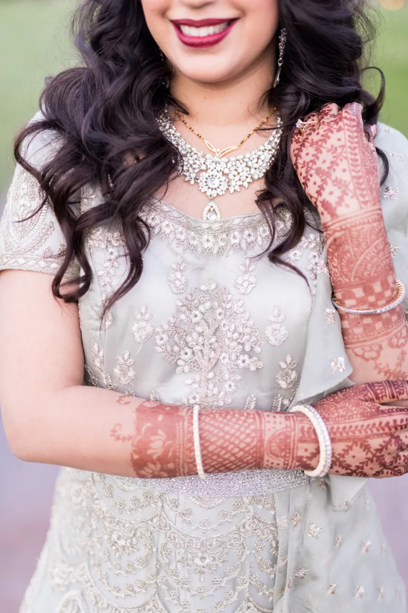 Close crop of the beaded reception gown, a gold necklace and the bride's henna covered arms