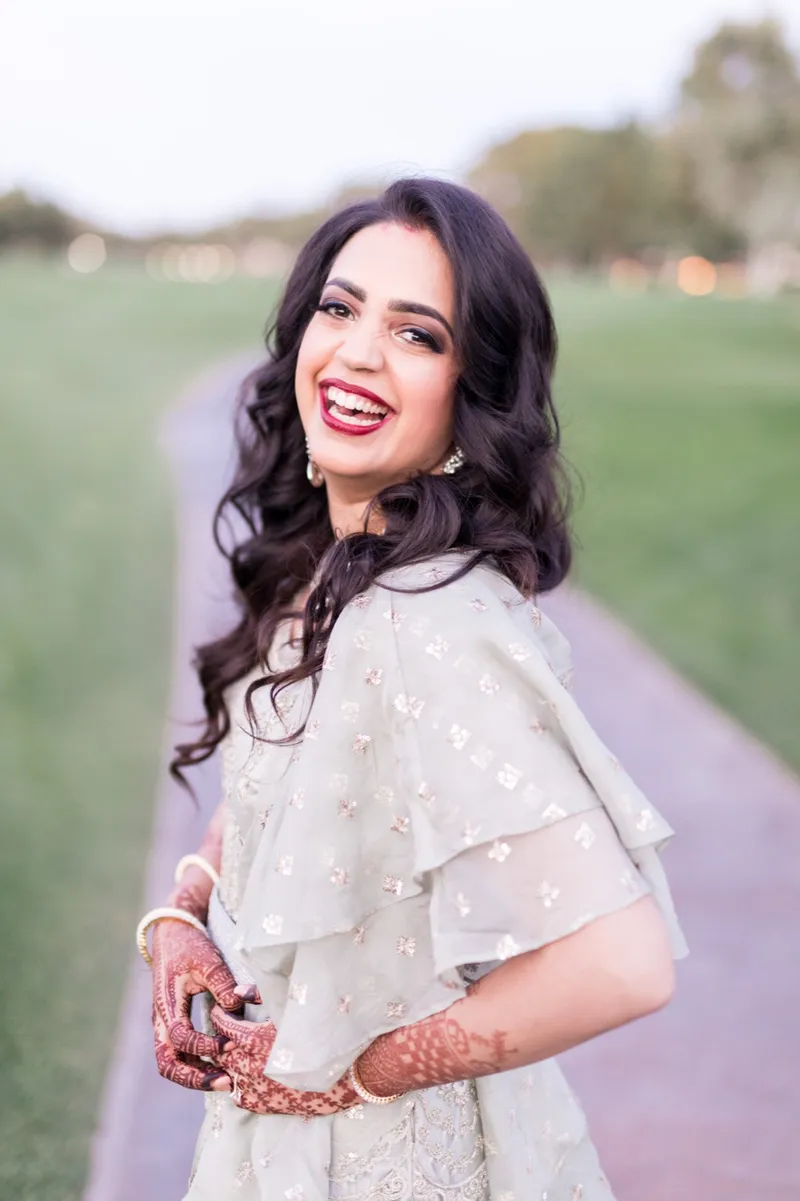 Bride laughing over her shoulder in her reception gown with the open course behind her