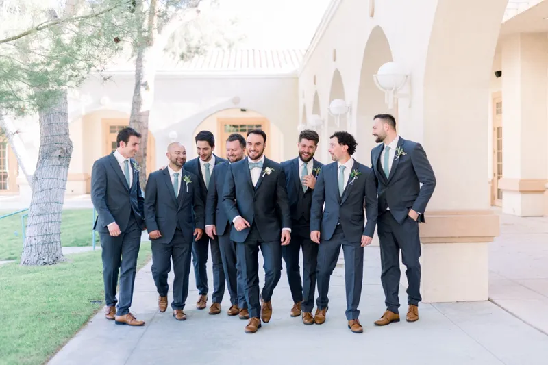 Groomsmen walking together along the shaded colonnade at the side of the church