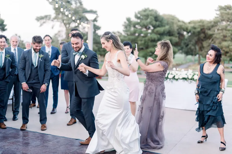 Bride and groom dancing in for their grand entrance as the wedding party claps them past the dinner tables