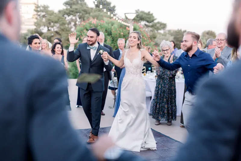 Bride and groom walking through a corridor of clapping guests with hands reaching in from both sides
