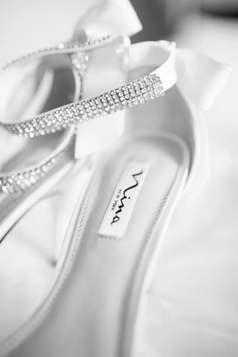 Black and white close view of the bride's heels with crystal straps across the toe