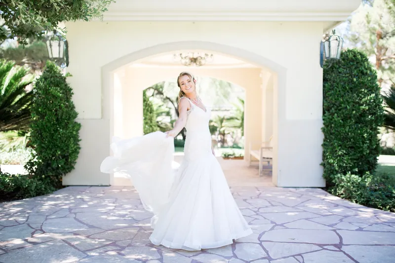 Bride looking up as she swings her gown across the flagstone under the archway
