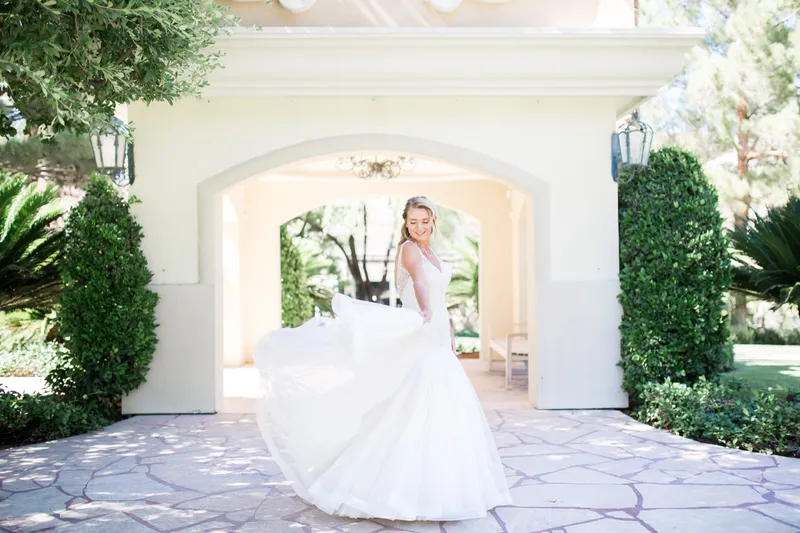 Bride's skirt fanned out wide across the stone paving as she turns beneath the arch