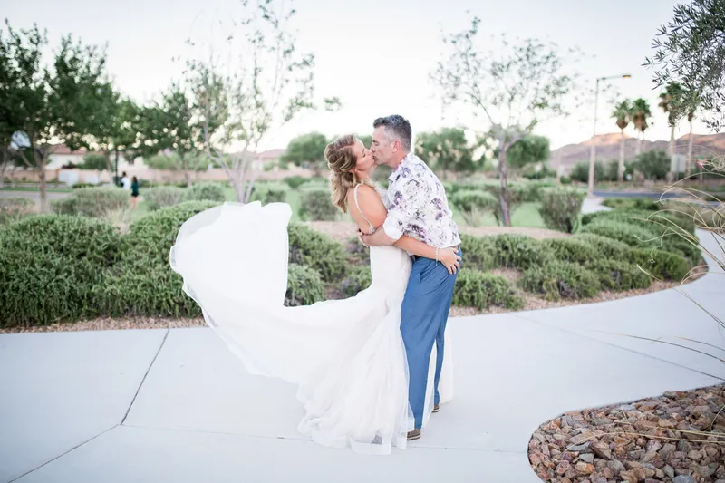 Couple kissing on the walkway with the bride's dress swirling around them both