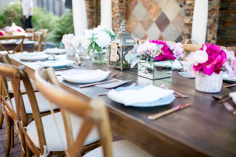 Long farm table set with pink peonies, pale blue plates and rose gold flatware down its length