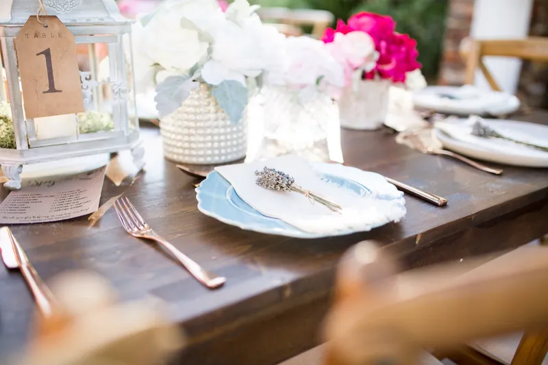 Table one marker propped in a lantern beside a vase of pink and white blooms