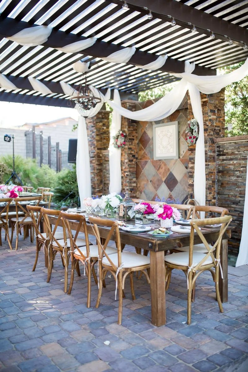 Farm tables under the draped pergola set and ready before the guests come out of the ceremony