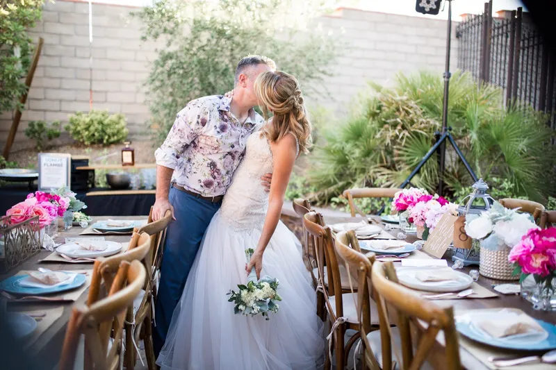 Bride and groom kissing beside the set reception tables in the backyard before anyone sits down