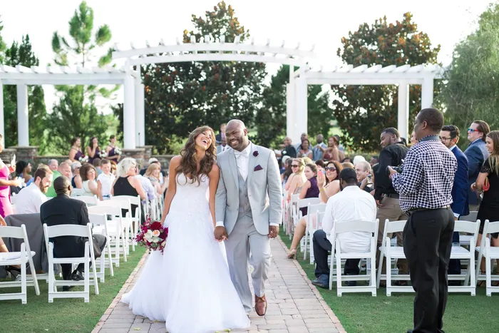 Newly married couple walking back down the aisle at sunset