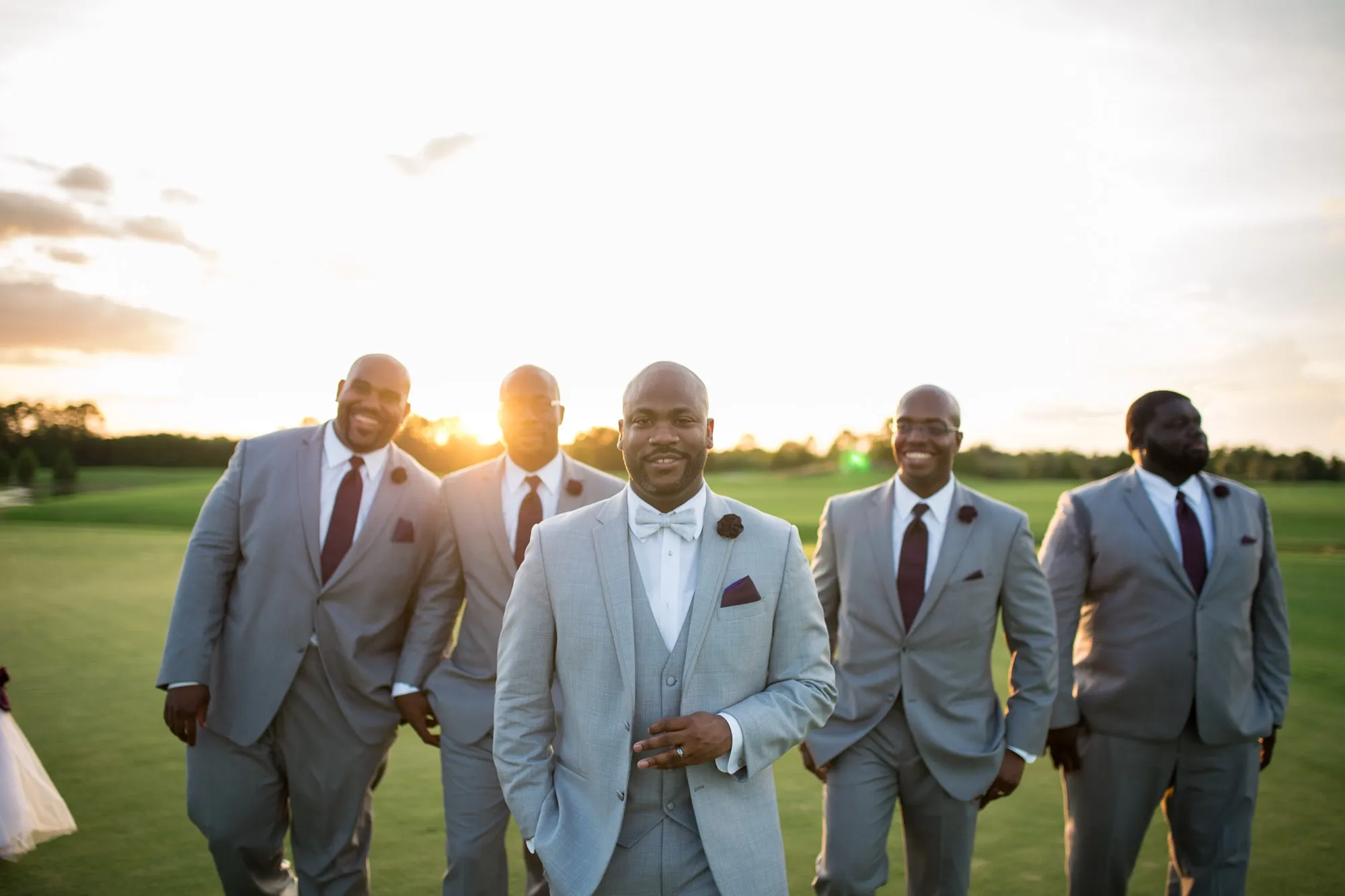 Groom and groomsmen laughing together at sunset