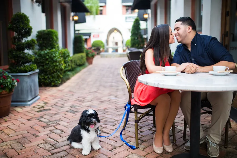 Couple sharing coffee at a sidewalk cafe with their dog