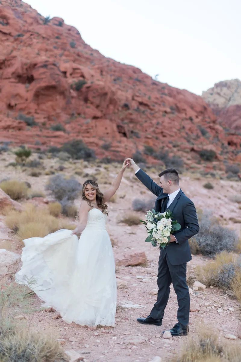 Groom spinning his bride under his arm, her skirt flaring and bouquet in his hand