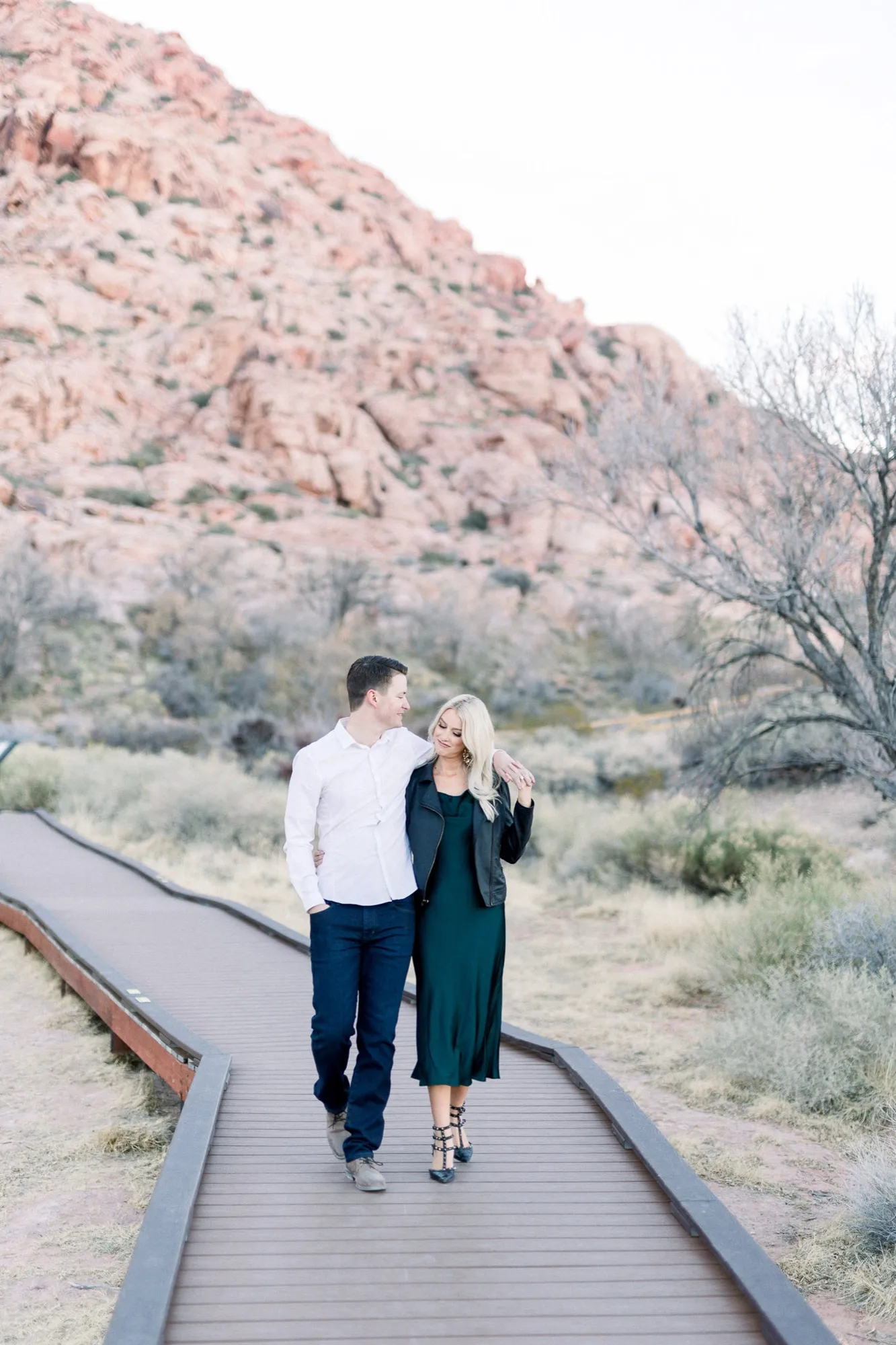 Couple walking hand in hand through the desert at Red Rock Canyon in the evening light